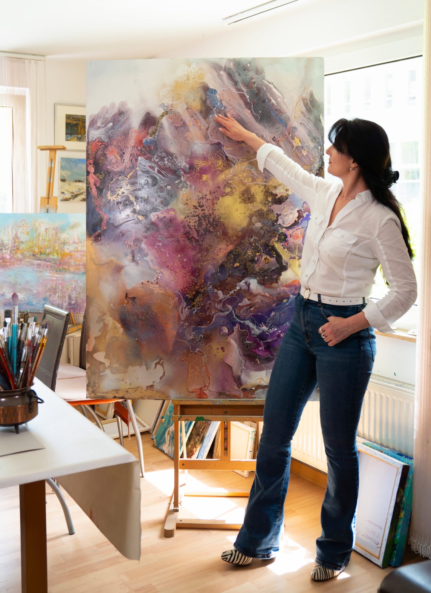 Irina Gerhardt in ihrem Atelier neben einer großen abstrakten Leinwand